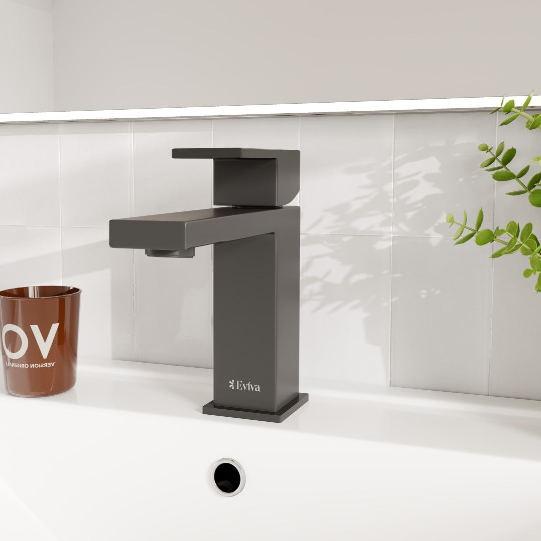 Black single-handle bathroom faucet with a waterfall spout and deckplate, displayed against a white tile background.