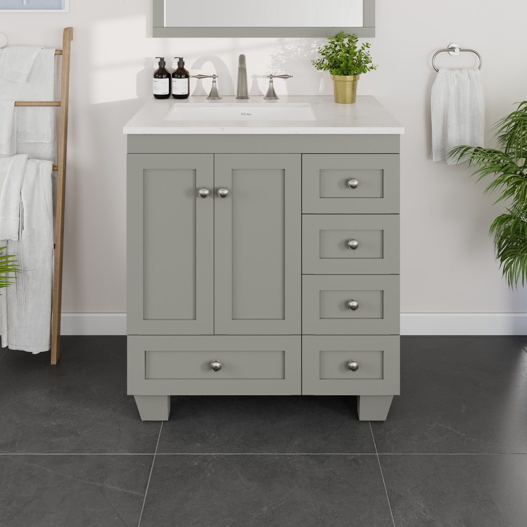 A gray single sink bath vanity with Carrara Quartz top and undermount porcelain sink, featuring multiple drawers and nickel hardware, set in a bathroom setting.