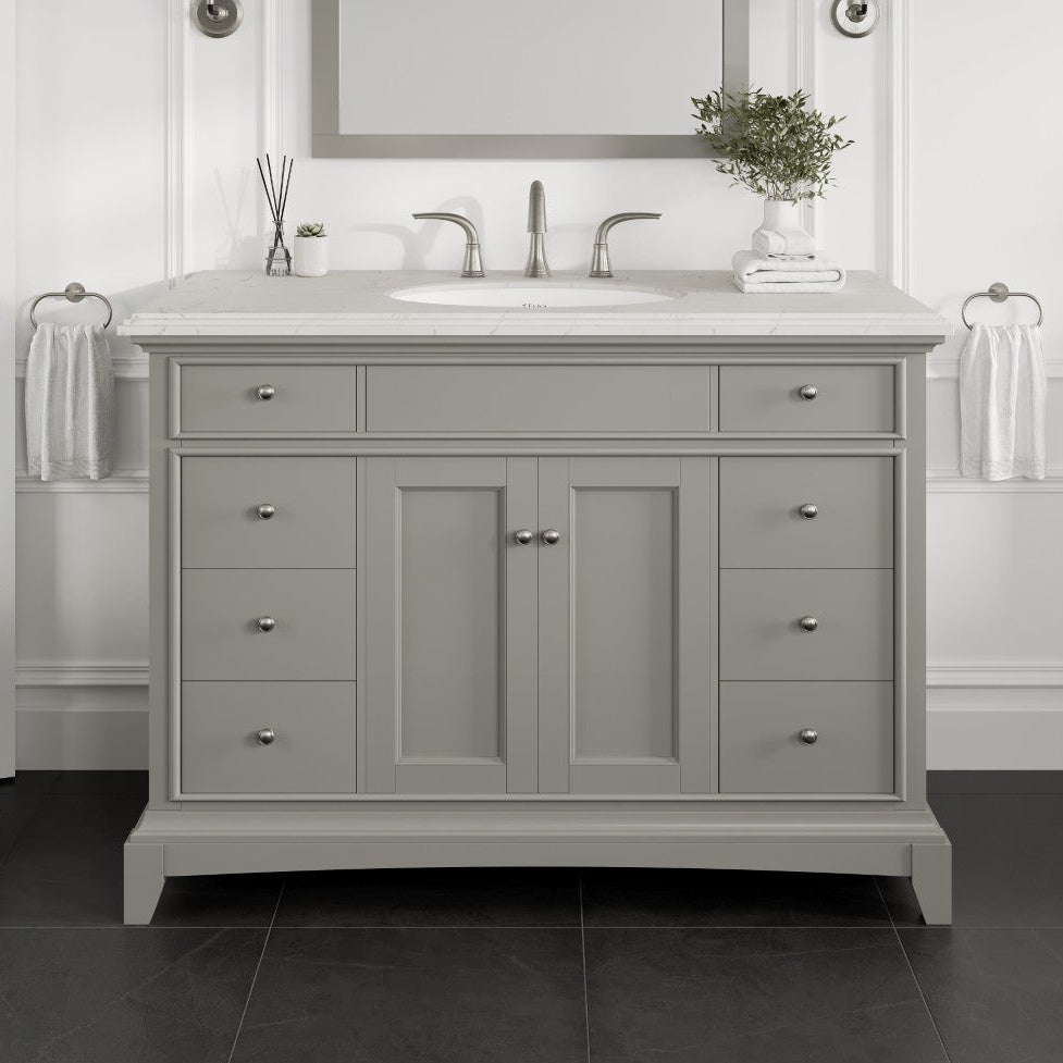 A gray single sink bath vanity with a Carrara quartz top, undermount porcelain sink, and wooden dovetail drawers.