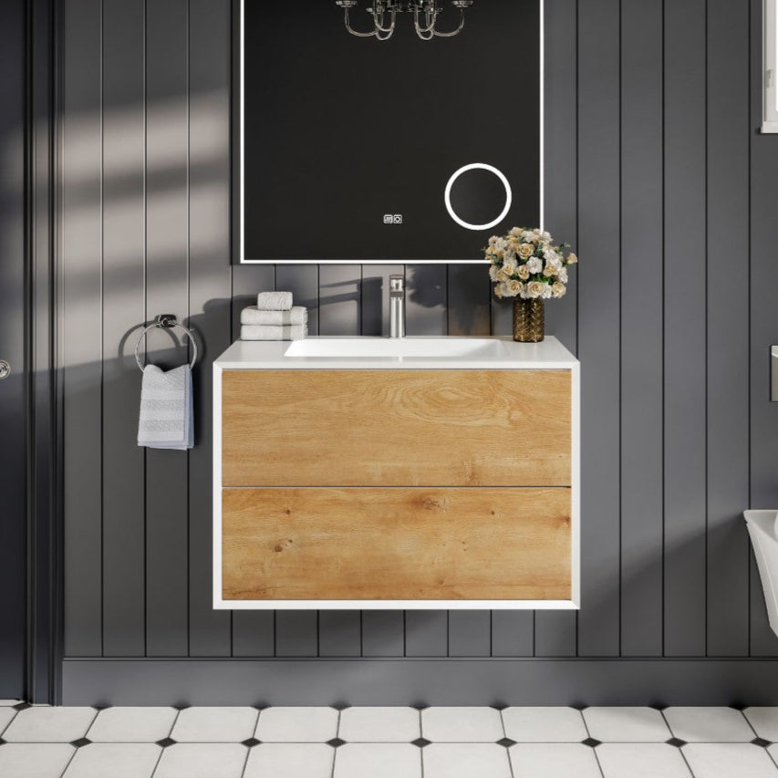 A wall-mounted single sink bath vanity with an oak finish cabinet and an acrylic top, featuring a mirror above the sink and a decorative bathroom setup.