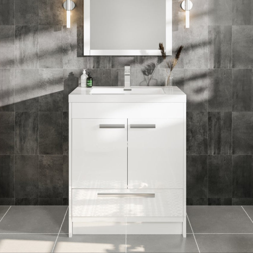 Modern white bathroom vanity with an acrylic top and integrated sink, featuring a glossy finish and soft-closing doors, set against a dark tiled wall with a mirror and wall lights above.