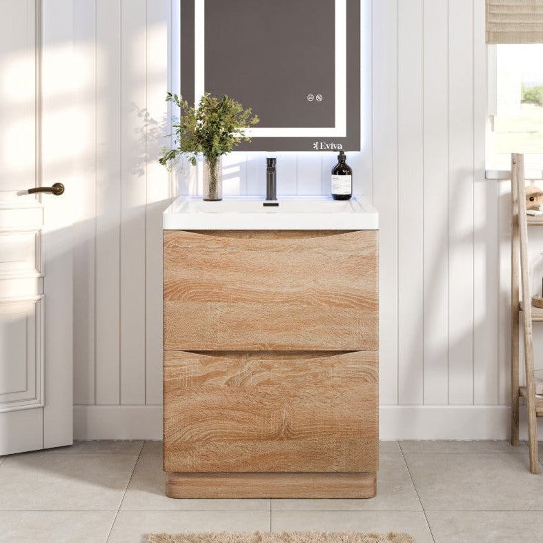 A white oak single sink bath vanity with an acrylic top and integrated sink, featuring a modern two-drawer design with soft-closing mechanisms. The image displays the vanity in a stylish bathroom setting, complemented by a large mirror above and bathroom accessories to the side.