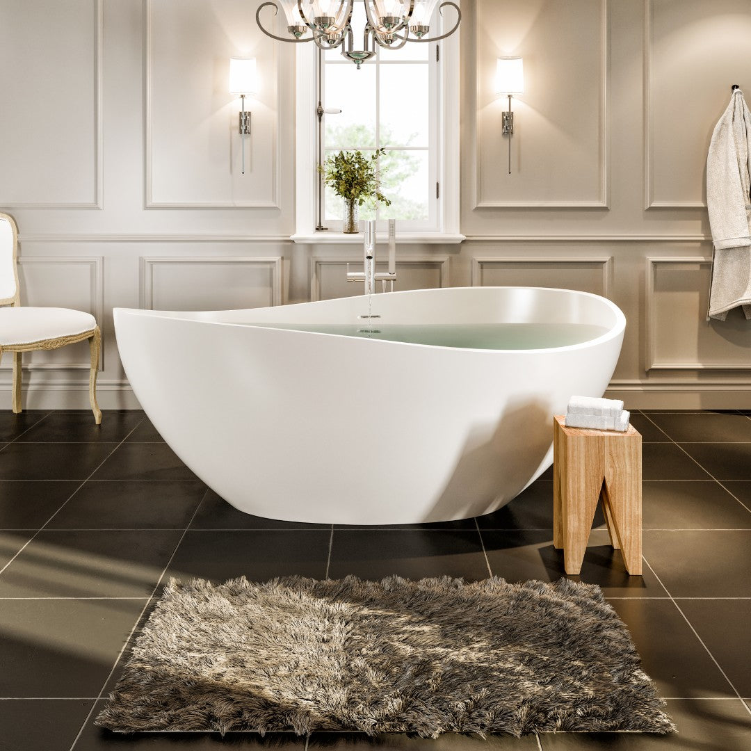 A matte white oval solid surface freestanding bathtub positioned in a bathroom setting, with a teardrop-shaped design.