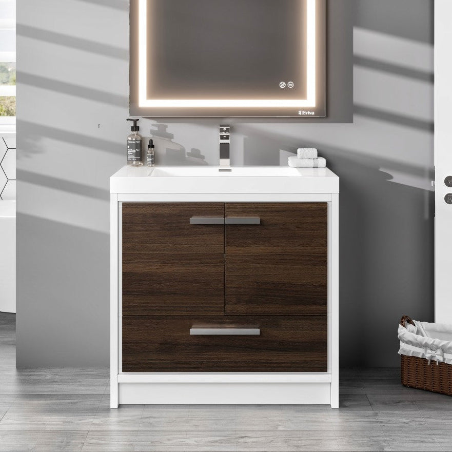 A modern bathroom vanity featuring a gray oak finish with a white acrylic countertop, integrated sink, and chrome hardware. The image shows the vanity from a front angle with an illuminated mirror above it, set in a bathroom setting.