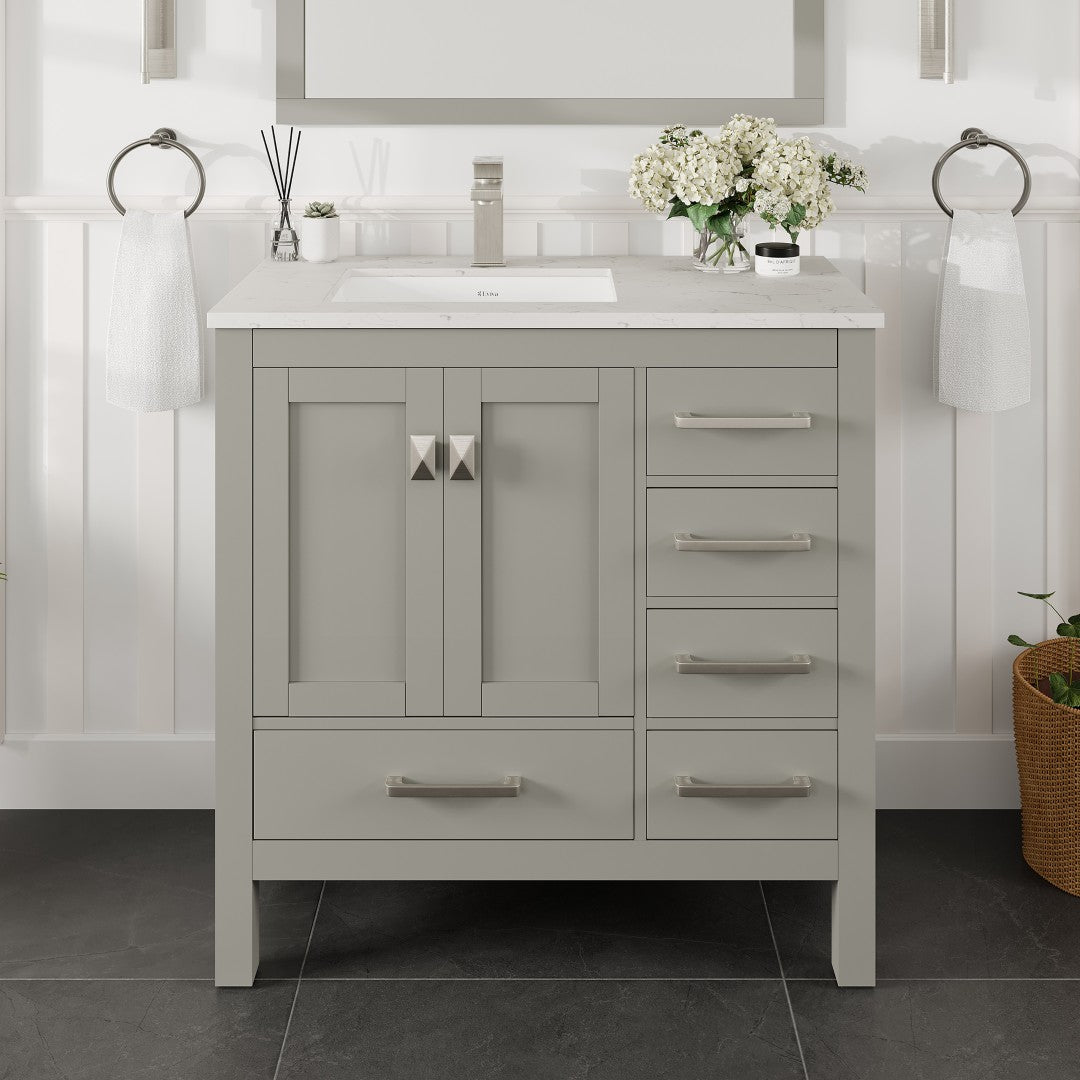 A gray single sink bath vanity with a Carrara quartz top and undermount porcelain sink, featuring stainless steel brushed nickel hardware.
