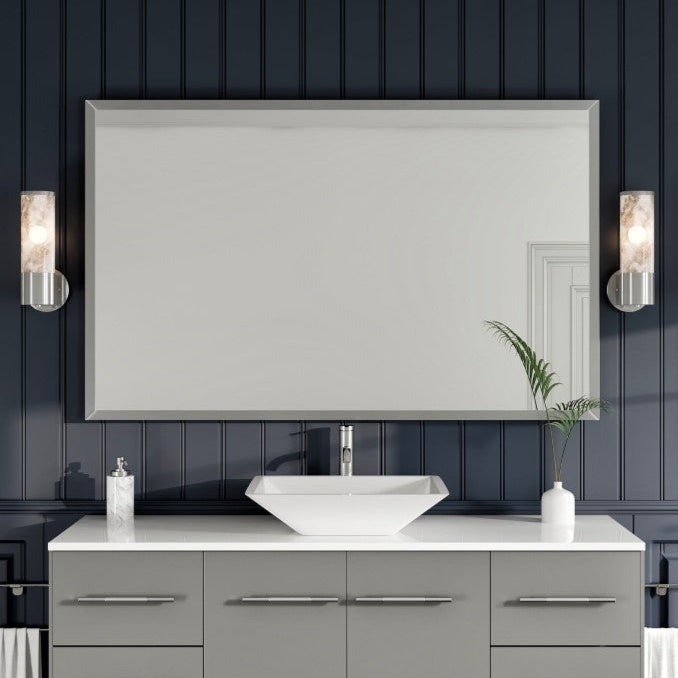 A modern bathroom setting featuring a rectangular brushed nickel metal framed mirror with straight edges, mounted on a wall with dark paneling.