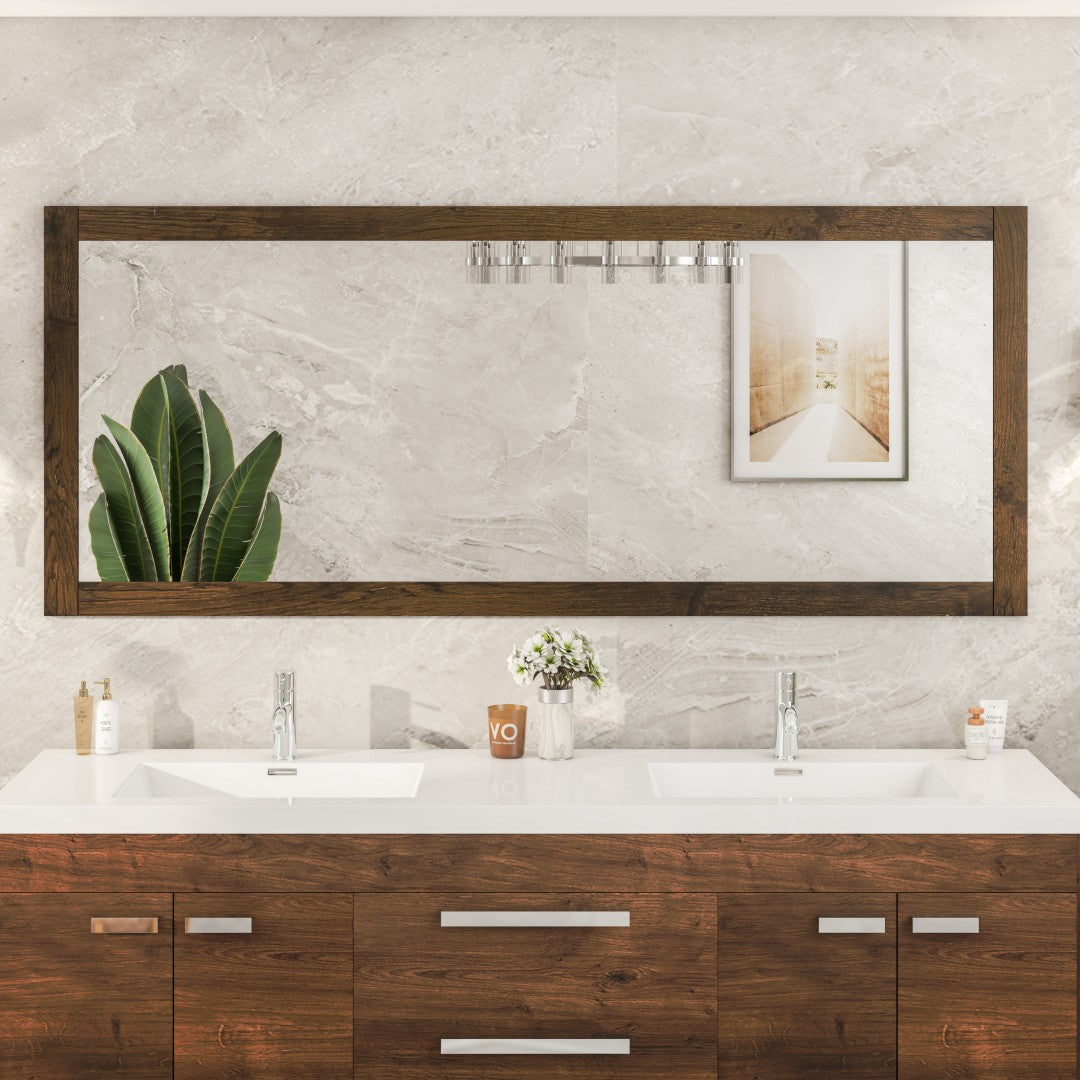 A rectangular rosewood wooden framed mirror mounted on a wall above a bathroom vanity, with a burst proof glass surface and beveled edges.