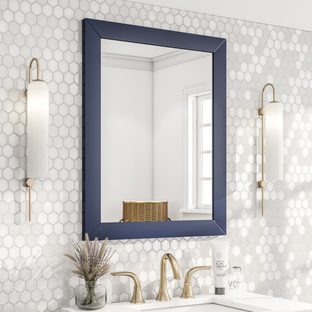A dark blue framed mirror hanging on a light-colored wall with scone lights on the side.