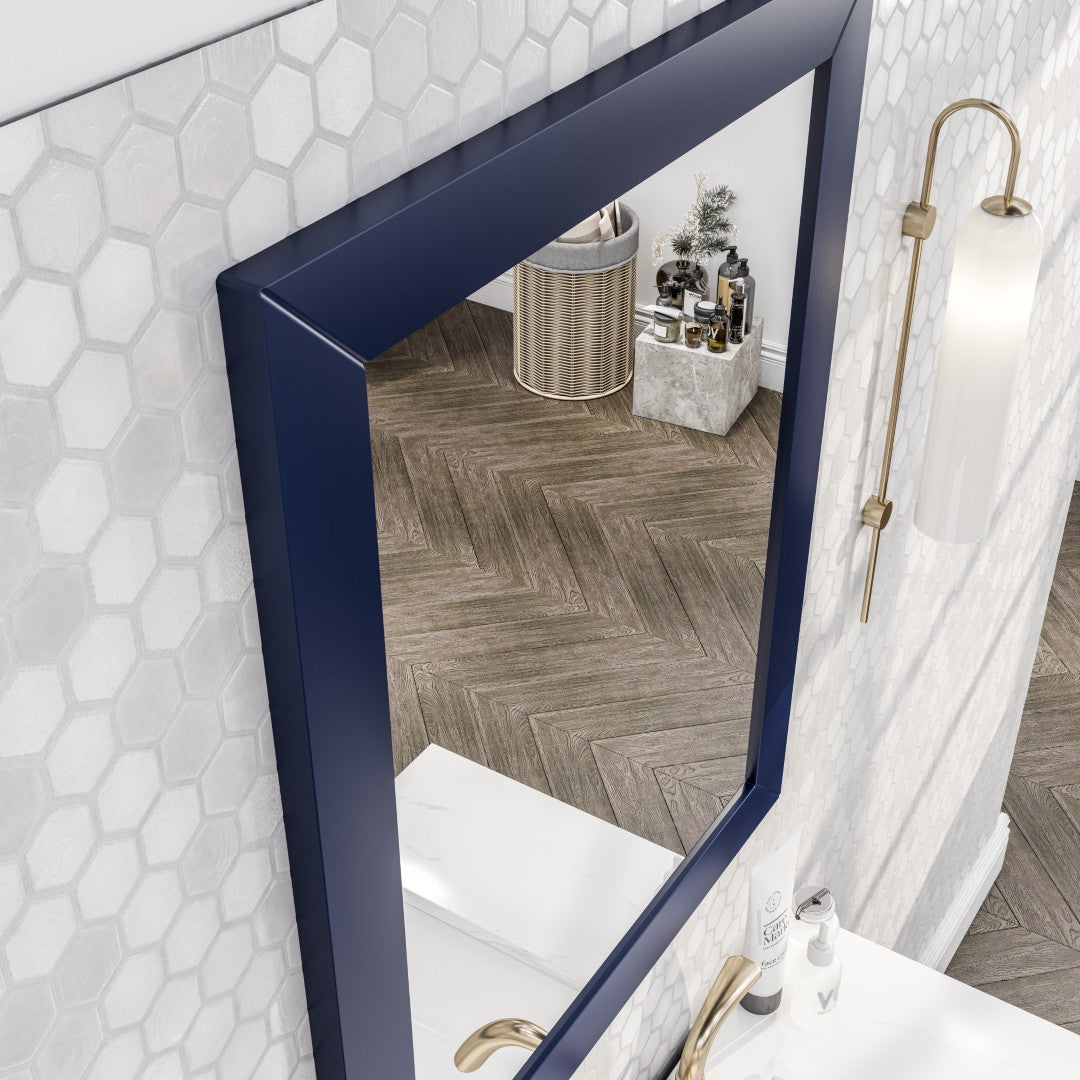 A dark blue framed mirror hanging on a light-colored wall with scone lights on the side.
