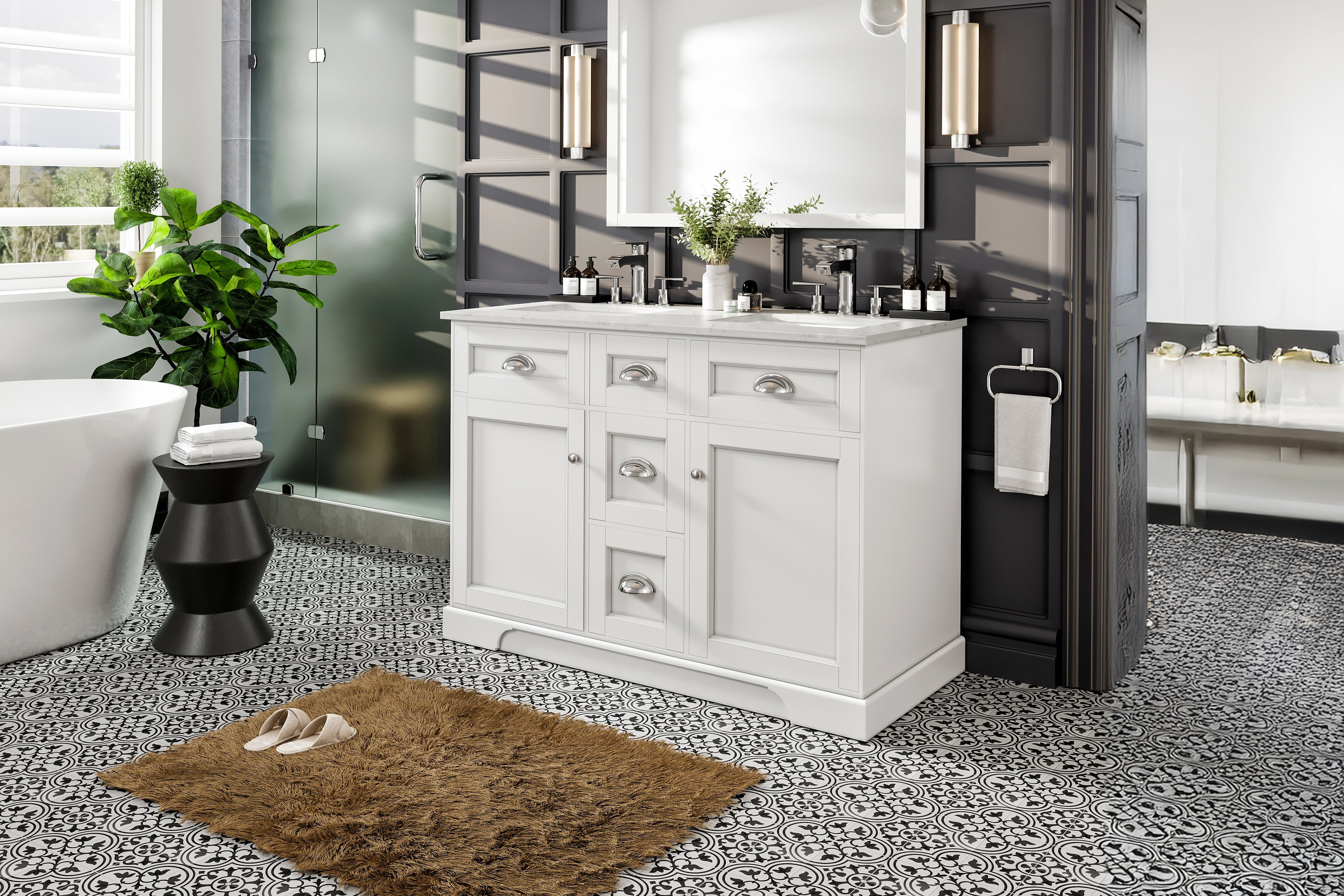 A white freestanding modern bathroom vanity with a double sink and silver hardware against a dark gray accent wall showing patterned tile flooring and bathtub