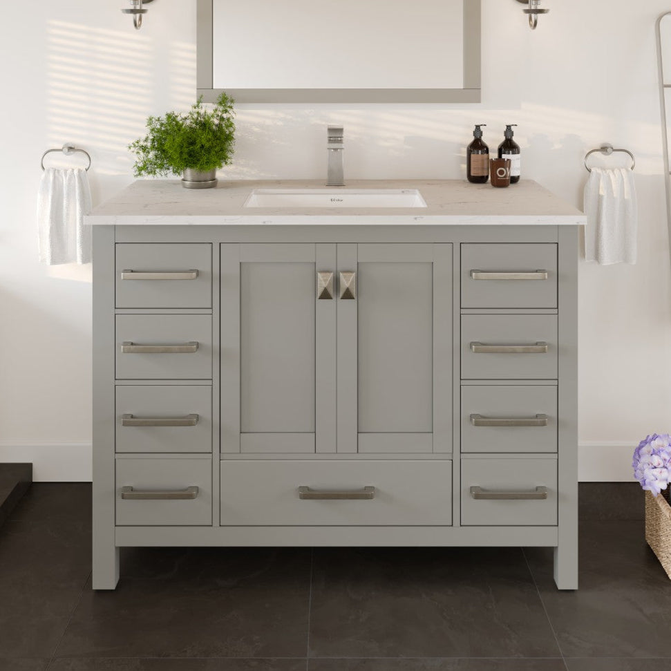 A gray single sink bath vanity with a Carrara quartz top and undermount porcelain sink, featuring stainless steel brushed nickel hardware.