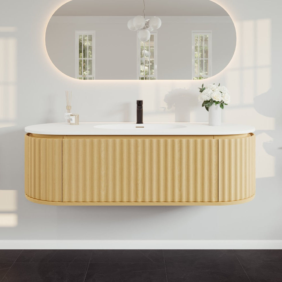 A wall-mounted, natural oak bathroom vanity with a solid surface top and integrated sink, featuring a fluted pattern with vertical grooves and rounded edges.