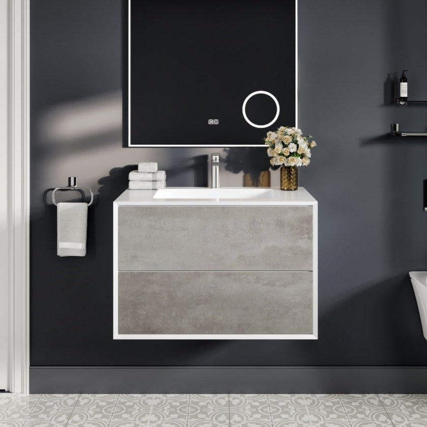 A modern wall-mounted bathroom vanity with a concrete gray cabinet and white acrylic countertop, featuring an integrated sink, mirror, and towel rack, set against a dark wall with a door and shelves in the background.