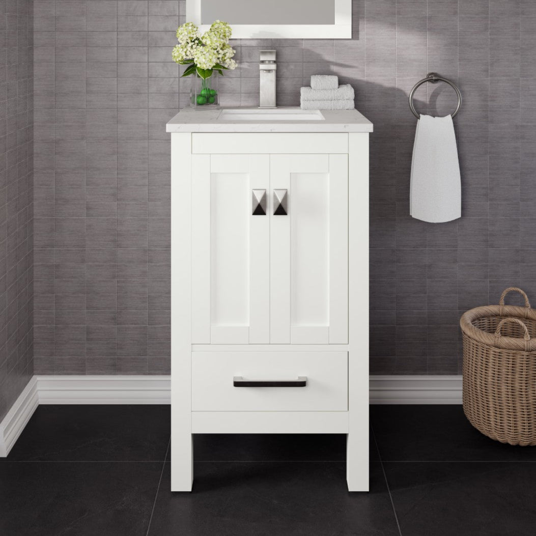 A white single sink bath vanity with a Carrara quartz top and undermount porcelain sink, featuring stainless steel hardware, placed against a bathroom backdrop with a basket and a towel hanging on the wall.