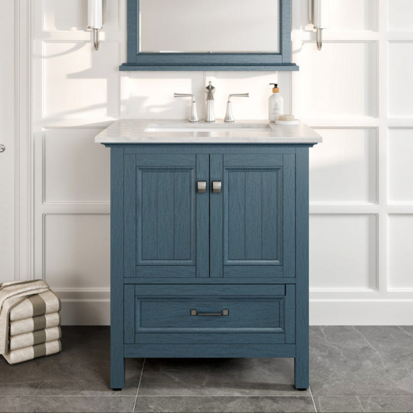 A traditional style bathroom vanity with ash blue finish, featuring a marble top, sink, and mirror, set against a white tiled wall.