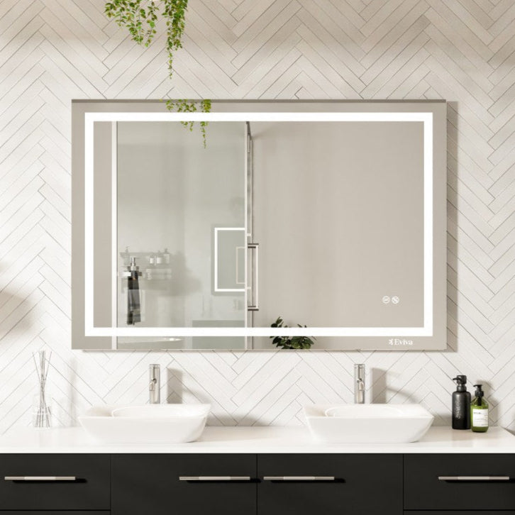 A rectangular, frameless mirror with LED lighting installed above a bathroom vanity. The mirror has a black frame and an aluminum back, and is equipped with a touch sensor.