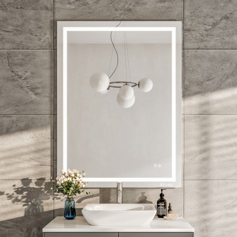 A modern bathroom scene featuring a rectangular frameless mirror with LED lighting  above a gray vanity cabinet with a white sink.