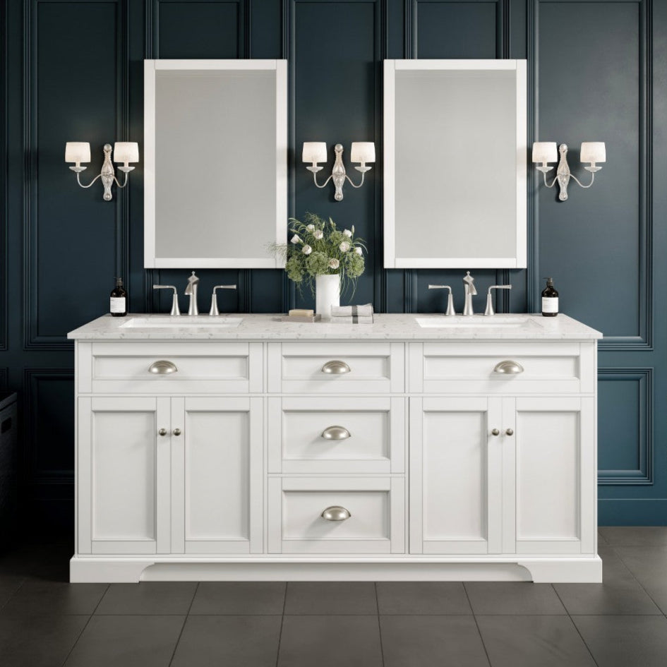 A white double sink bathroom vanity with a Carrara quartz top, undermount porcelain sinks, and stainless steel handles, set against a blue wall with dark trim.
