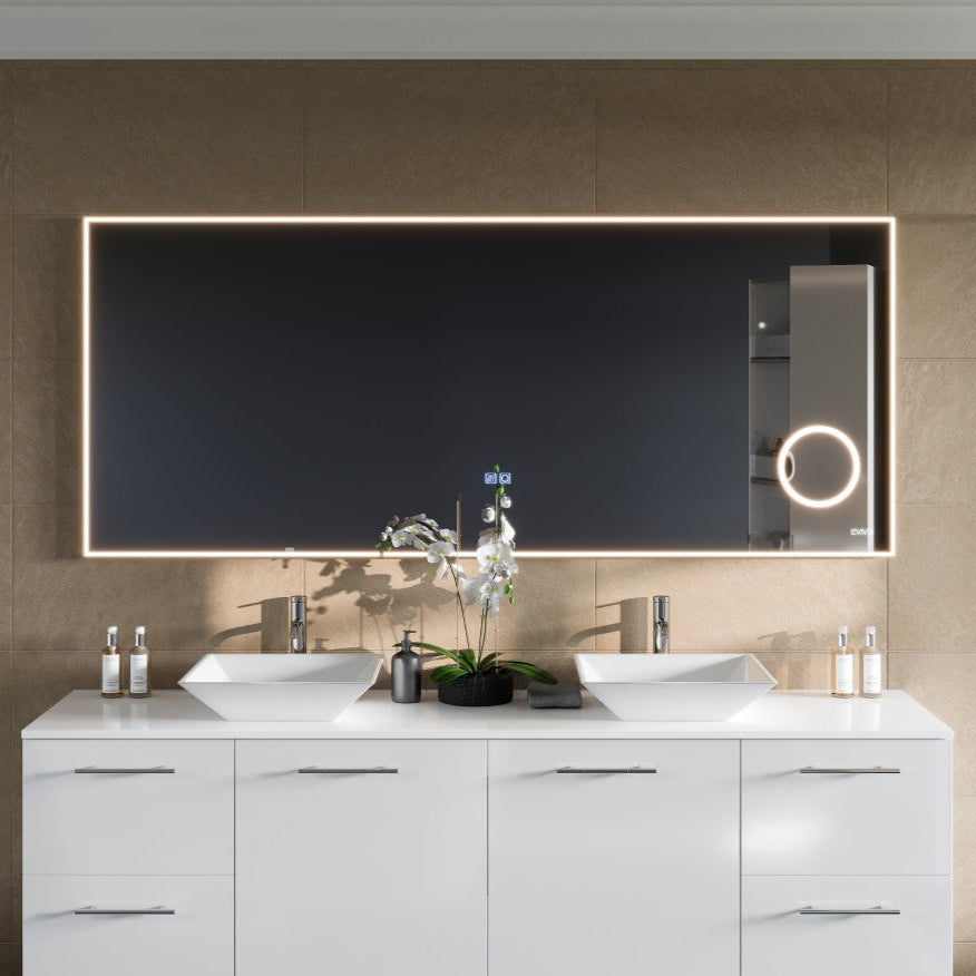 Modern rectangular LED bathroom mirror with a chrome aluminum framed design, mounted above a vanity with dual sinks.