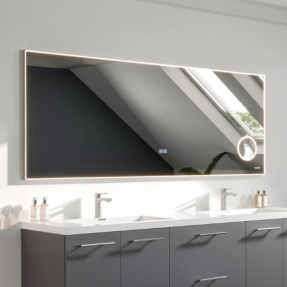 A modern rectangular LED bathroom mirror with a chrome aluminum framed design, installed above a grey vanity with dual sinks.