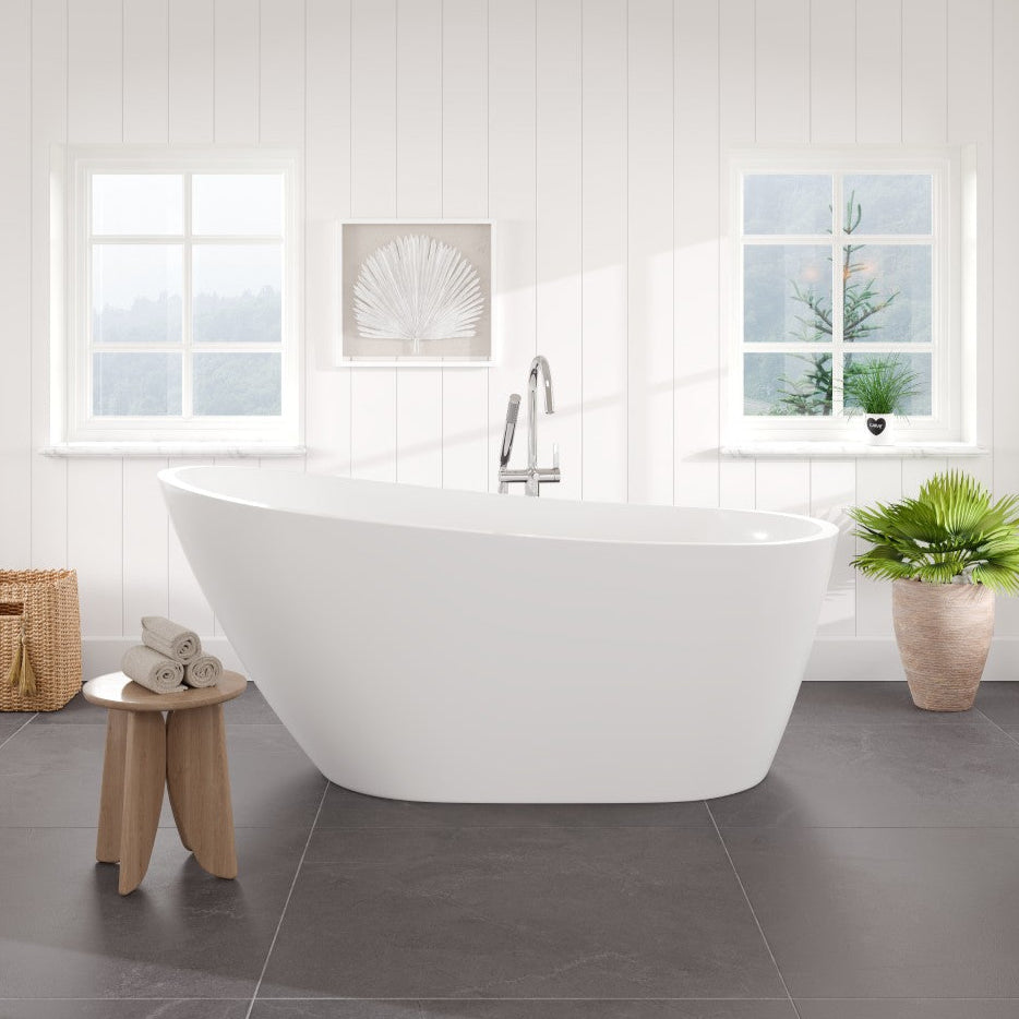 A glossy white acrylic slipper freestanding bathtub positioned in a bathroom setting with a light color scheme, accompanied by a chrome faucet and nearby decorative elements.