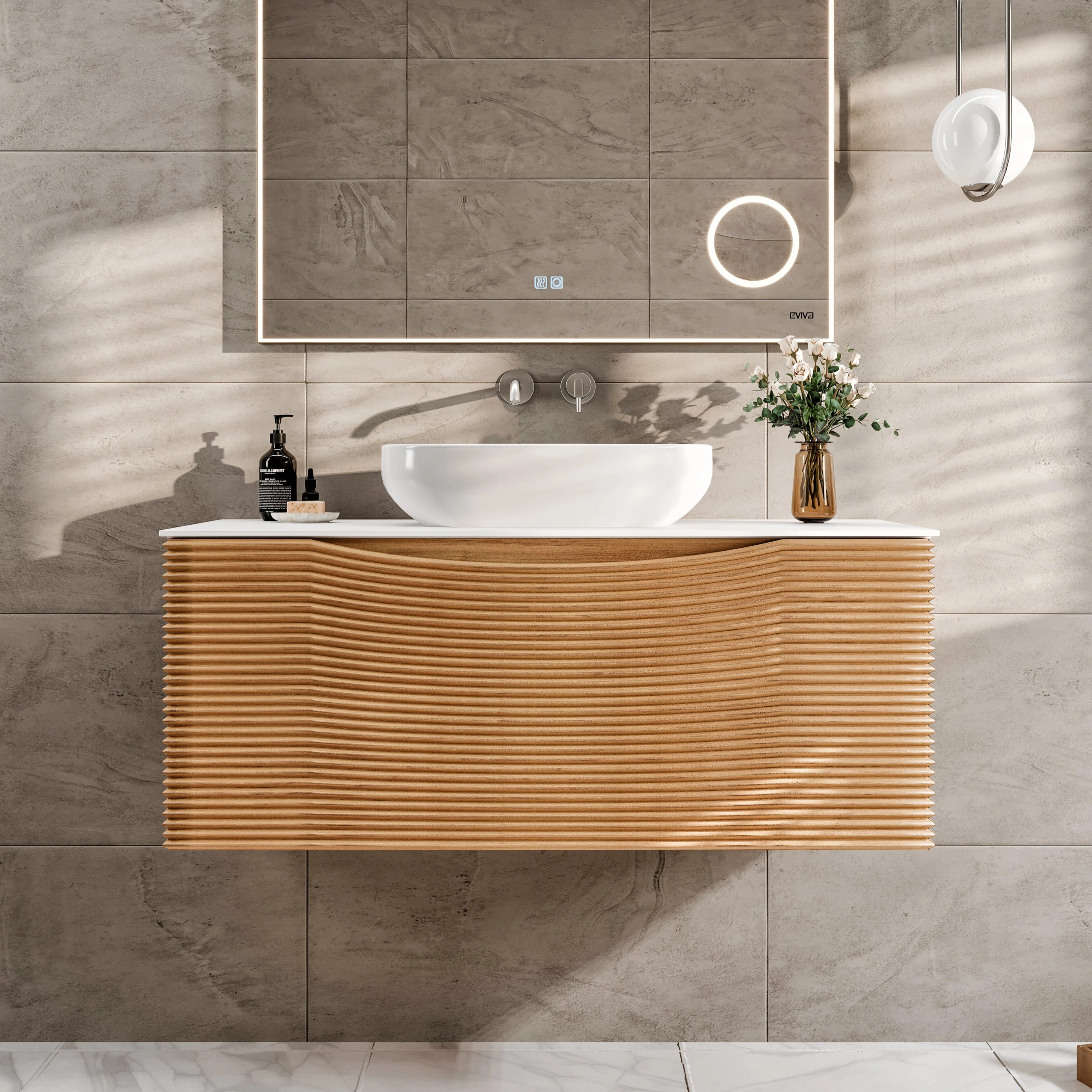 A wall-mounted single sink bath vanity with a medium oak wood finish and a solid surface top, featuring a vessel sink. The vanity is installed in a bathroom with tiled walls and a circular mirror above it.