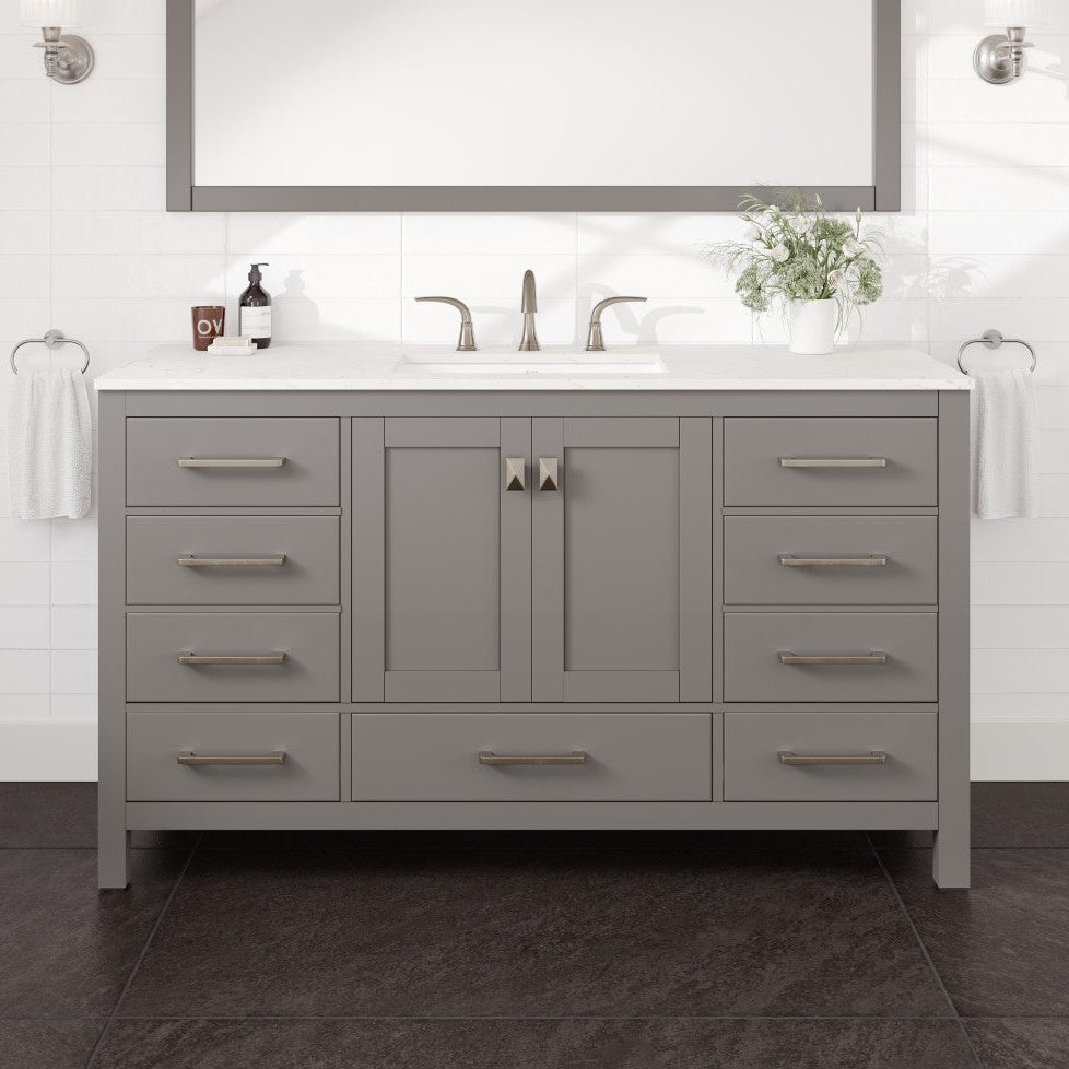A gray single sink bath vanity with a Carrara quartz top, undermount porcelain sink, and gold hardware, displayed in a bathroom setting.